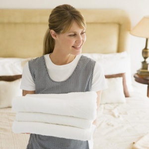 maid-holding-towels-in-hotel-room-smiling maid-holding-towels-in-hotel-room-smiling