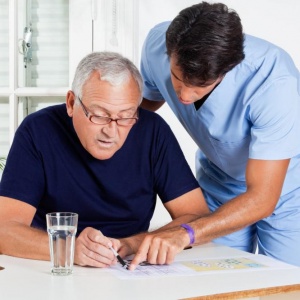 male-nurse-helping-senior-man-in-solving-puzzle male-nurse-helping-senior-man-in-solving-puzzle